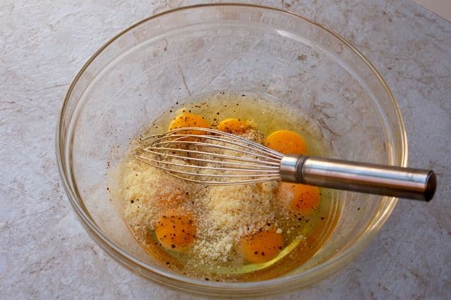 Cracked Eggs into a bowl with Parmesan