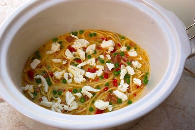 Slow Cooker Spaghetti Frittata ingredients in white crock pot with mozzarella cheese on top