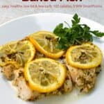Baked fish topped with lemon slices and fresh herbs on a white plate