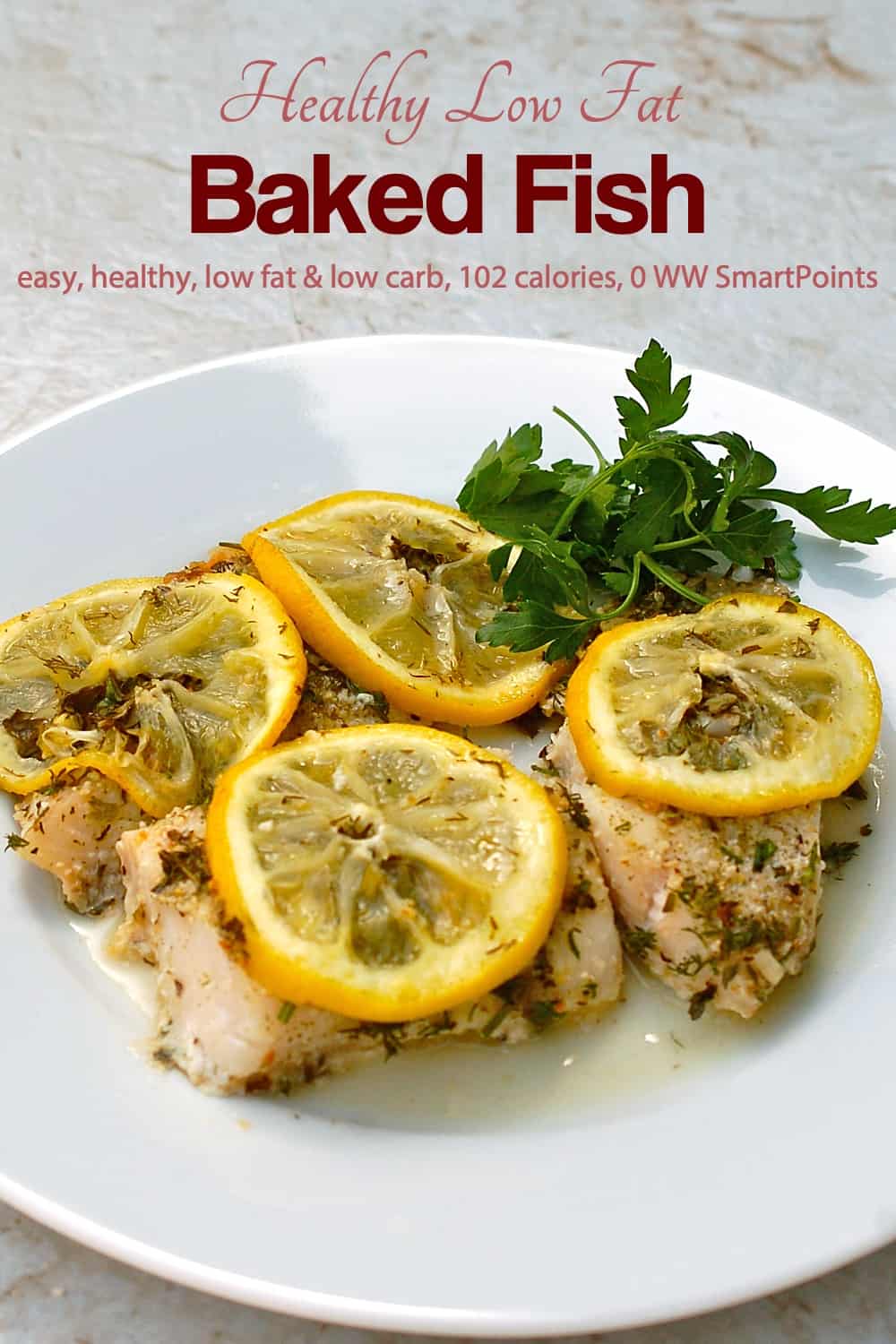 Baked fish topped with lemon slices and fresh herbs on a white plate