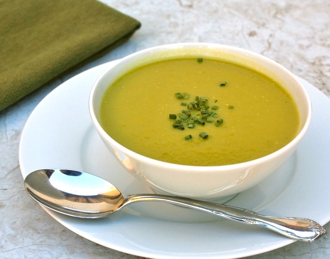 Creamy Asparagus Soup in a white bowl topped with chives.