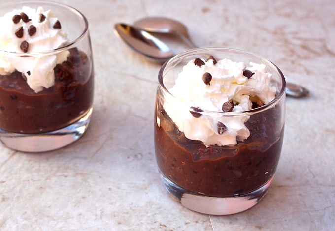 Two dessert glasses with chocolate tapioca pudding garnished with whipped cream and chocolate chips