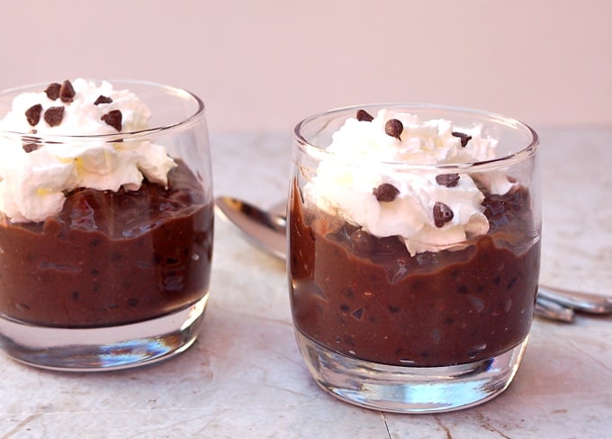 Two small dessert glasses with chocolate tapioca pudding, whipped cream and mini chocolate chips