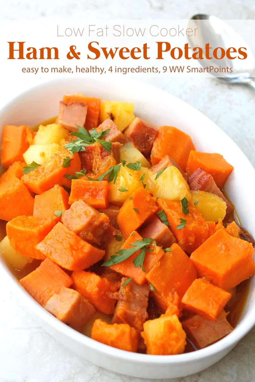 Cubed ham, sweet potatoes and pineapple in white casserole dish with serving spoon