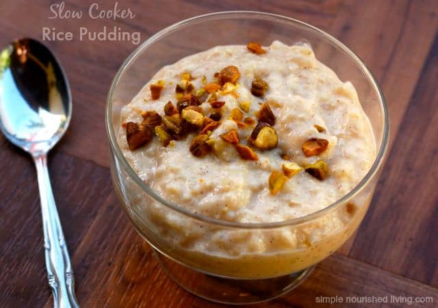 Slow Cooker Rice Pudding topped with chopped nuts in a dessert glass with spoon.