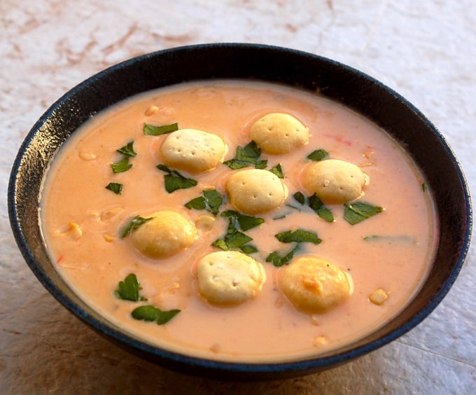 Bowl of spicy seafood chowder topped with parsley and chowder crackers