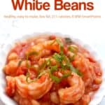 White beans with shrimp in light tomato sauce topped with sliced fresh basil in white bowl.