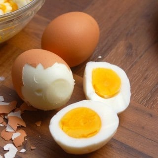 Brown Shelled Hard Boiled Eggs, One Partially Peeled, One Sliced in Half
