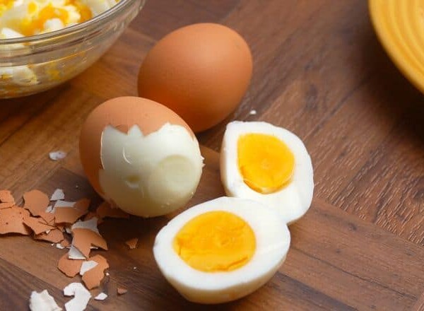 Brown Shelled Hard Boiled Eggs, One Partially Peeled, One Sliced in Half
