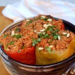 Three slow cooker couscous stuffed peppers in blue ceramic dish.