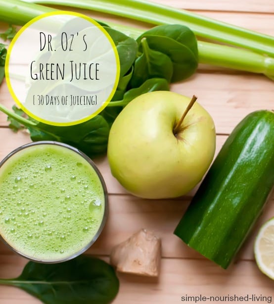 Juice ingredients on cutting board including appel, cucumber, spinach, celery, lime and ginger root along with glass of green juice.