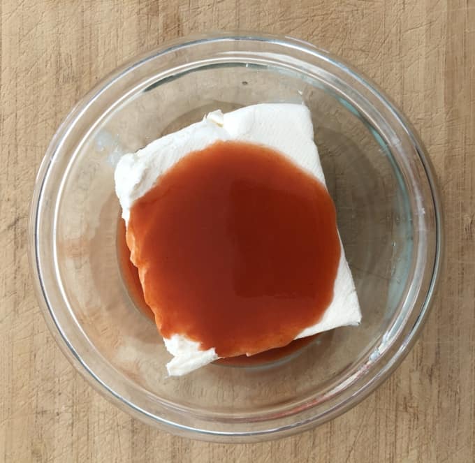 Neufchatel cream cheese and hot pepper sauce in small glass bowl.