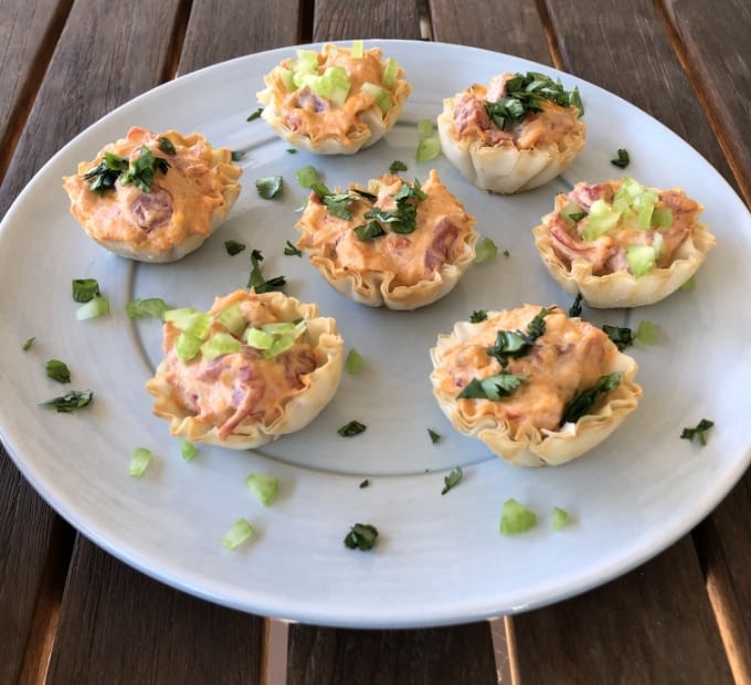 Mini baked buffalo chicken bites in phyllo shells and topped with chopped celery and cilantro.