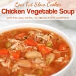 Bowl of chicken vegetable soup with carrots and beans in the foreground and another bowl of soup in the background
