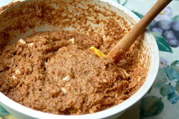 Mixing together apple bran muffin batter in a bowl with a wooden spoon