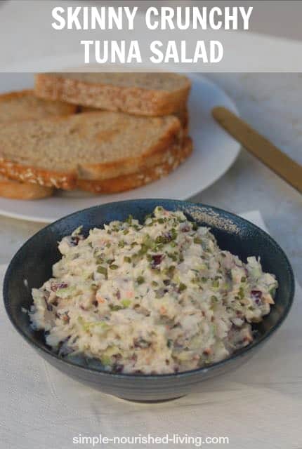 Tuna salad in blue pottery bowl with plate of toast in background.
