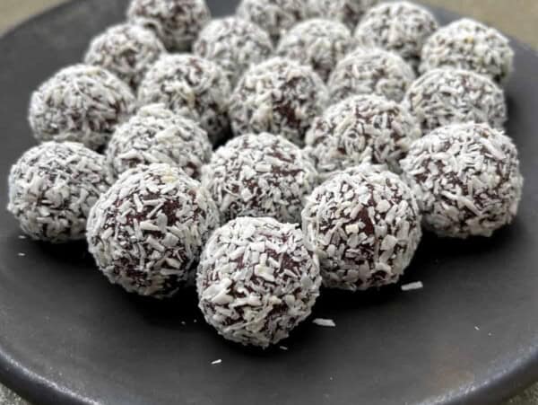 dark pottery plate with chocolate almond coconut truffles arranged in concentric circles