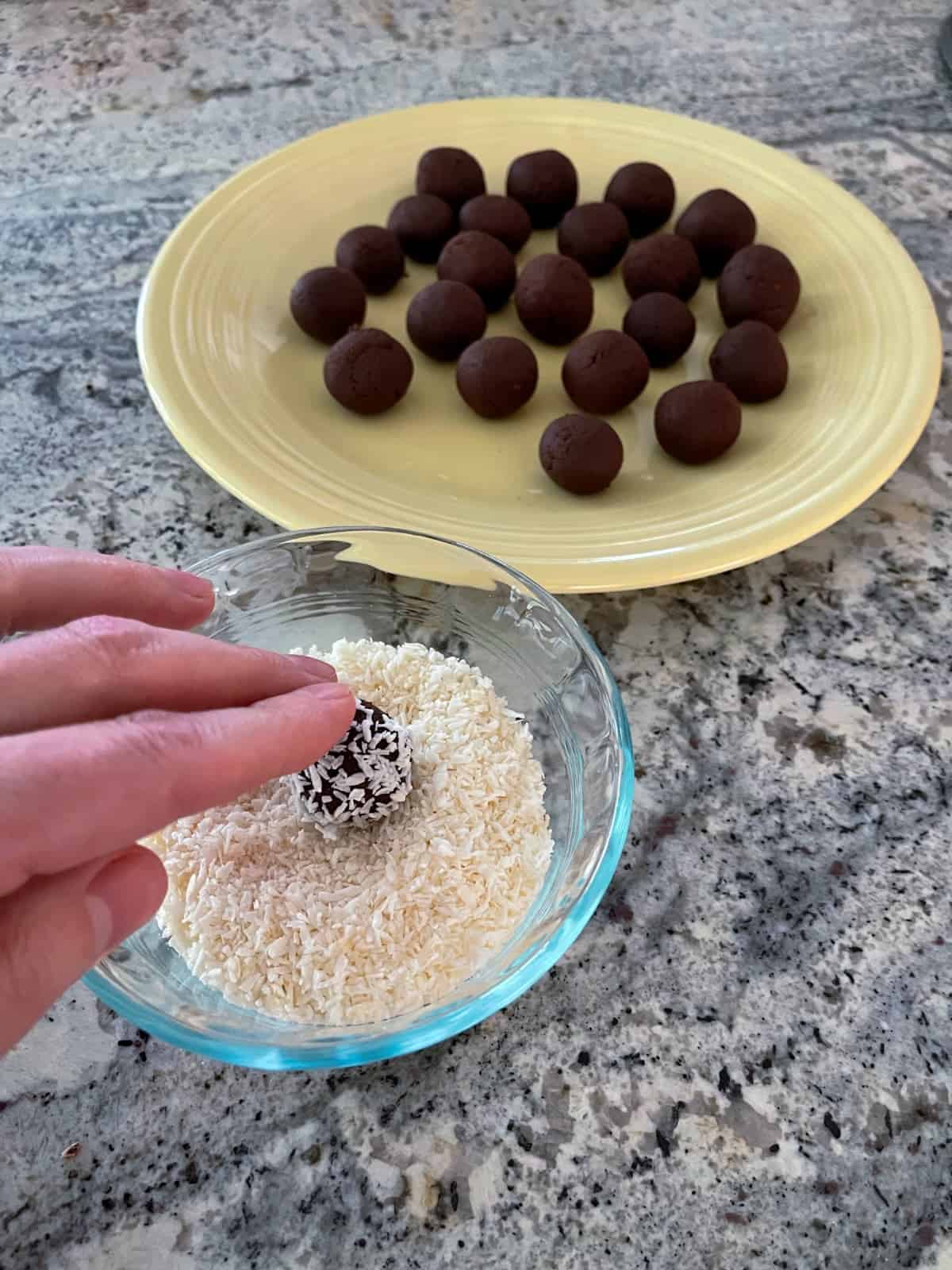 Rolling chocolate almond truffles in shredded coconut.