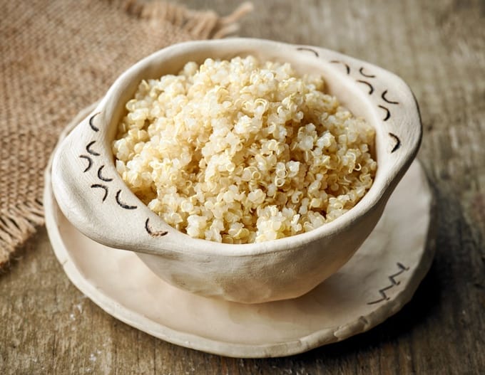 Bowl of cooked quinoa on wooden table