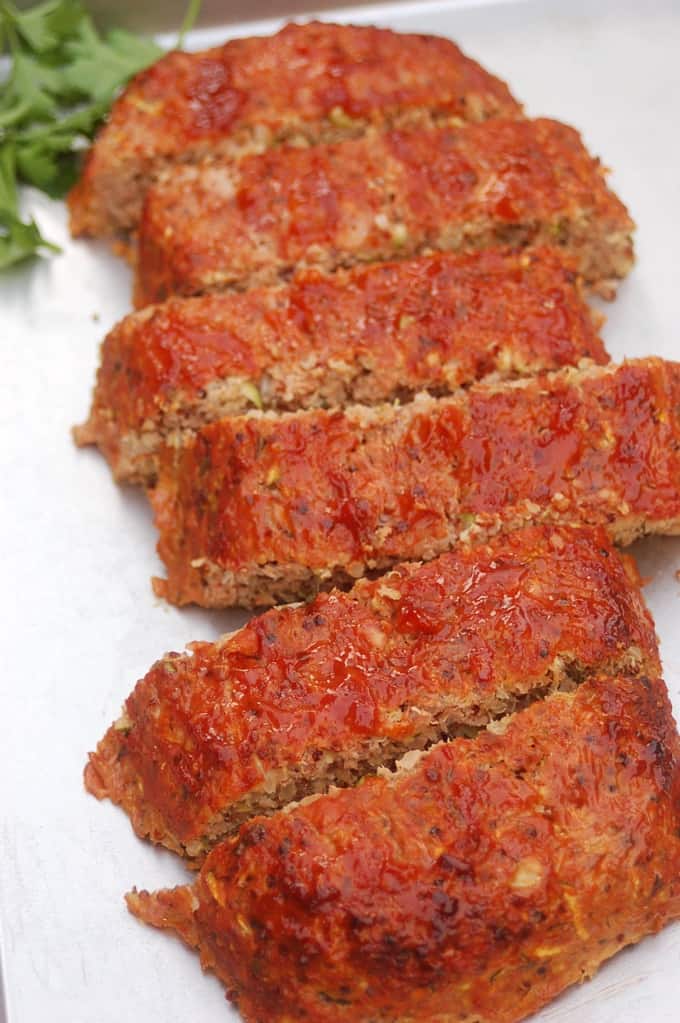 Slices of turkey meatloaf made with quinoa and zucchini on white serving platter