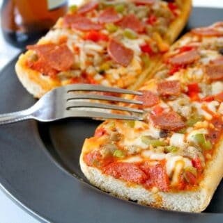 french bread pizza on a dark plate with fork digging in
