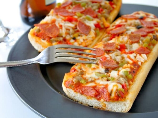 french bread pizza on a dark plate with fork digging in