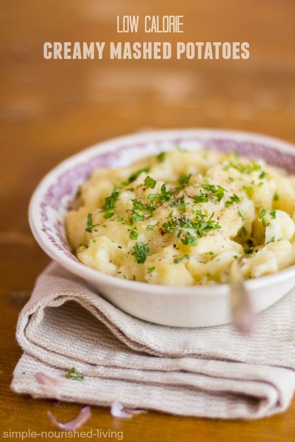 Creamy mashed potatoes in serving bowl topped with parsley, salt and pepper.