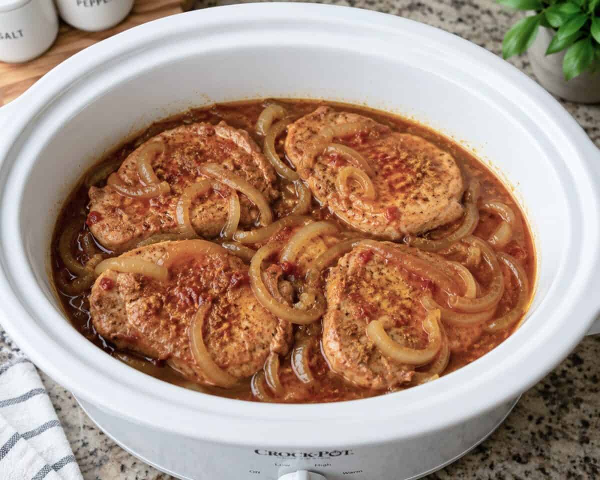 Slow cooker pork chops in white slow cooker.