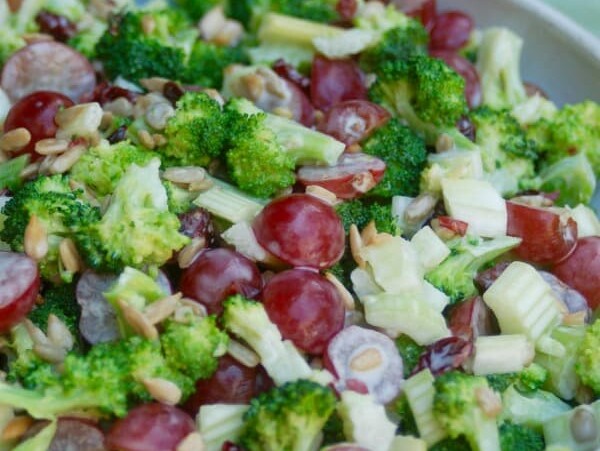 skinny broccoli salad in a ceramic bowl with green background