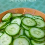 slices of english cucumber in a wooden bowl on aqua background