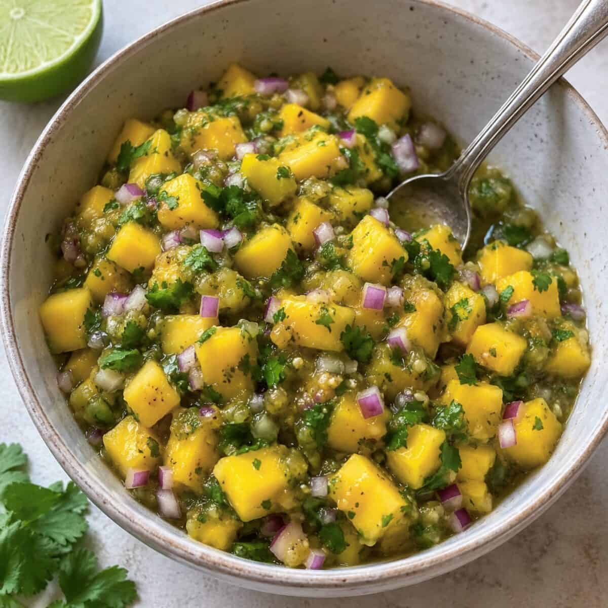 Fresh mango salsa in a ceramic serving bowl with spoon.