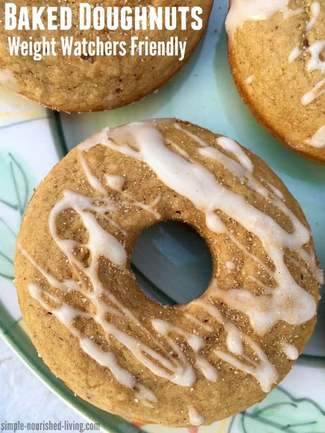 Baked apple cinnamon doughnuts drizzled with icing on a plate.