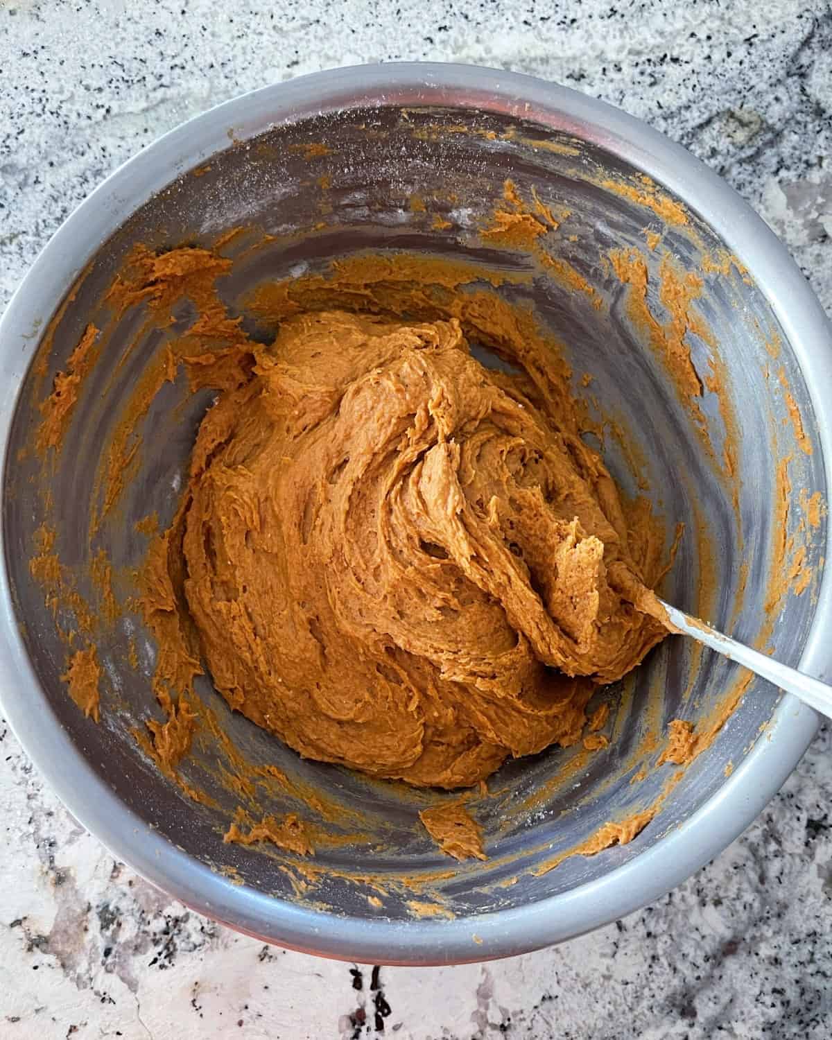Mixing spice cake mix and pumpkin puree in large mixing bowl with spoon.