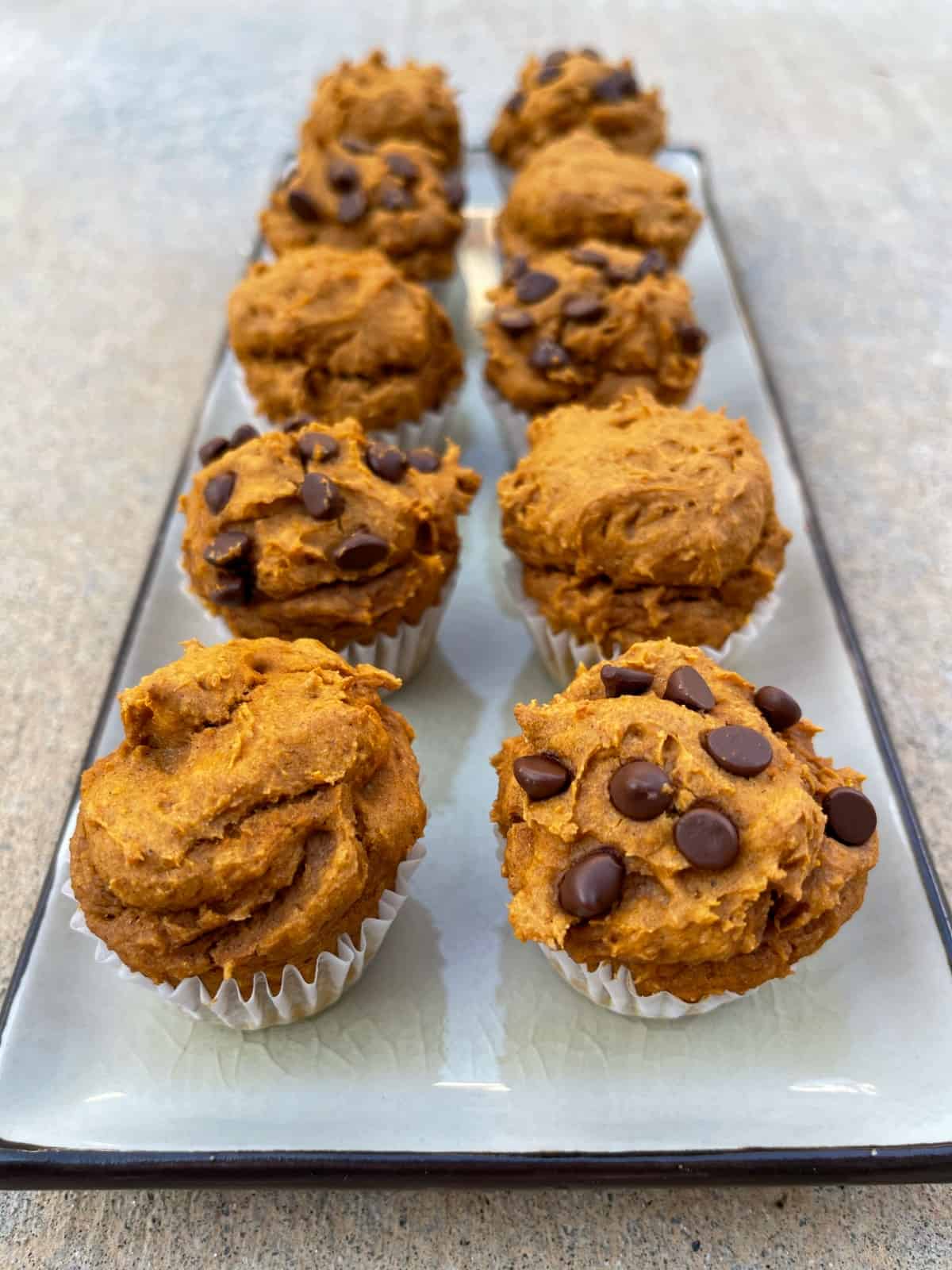 Eight mini pumpkin spice cake mix muffins (half plain and half with miniature chocolate chips) on serving platter.