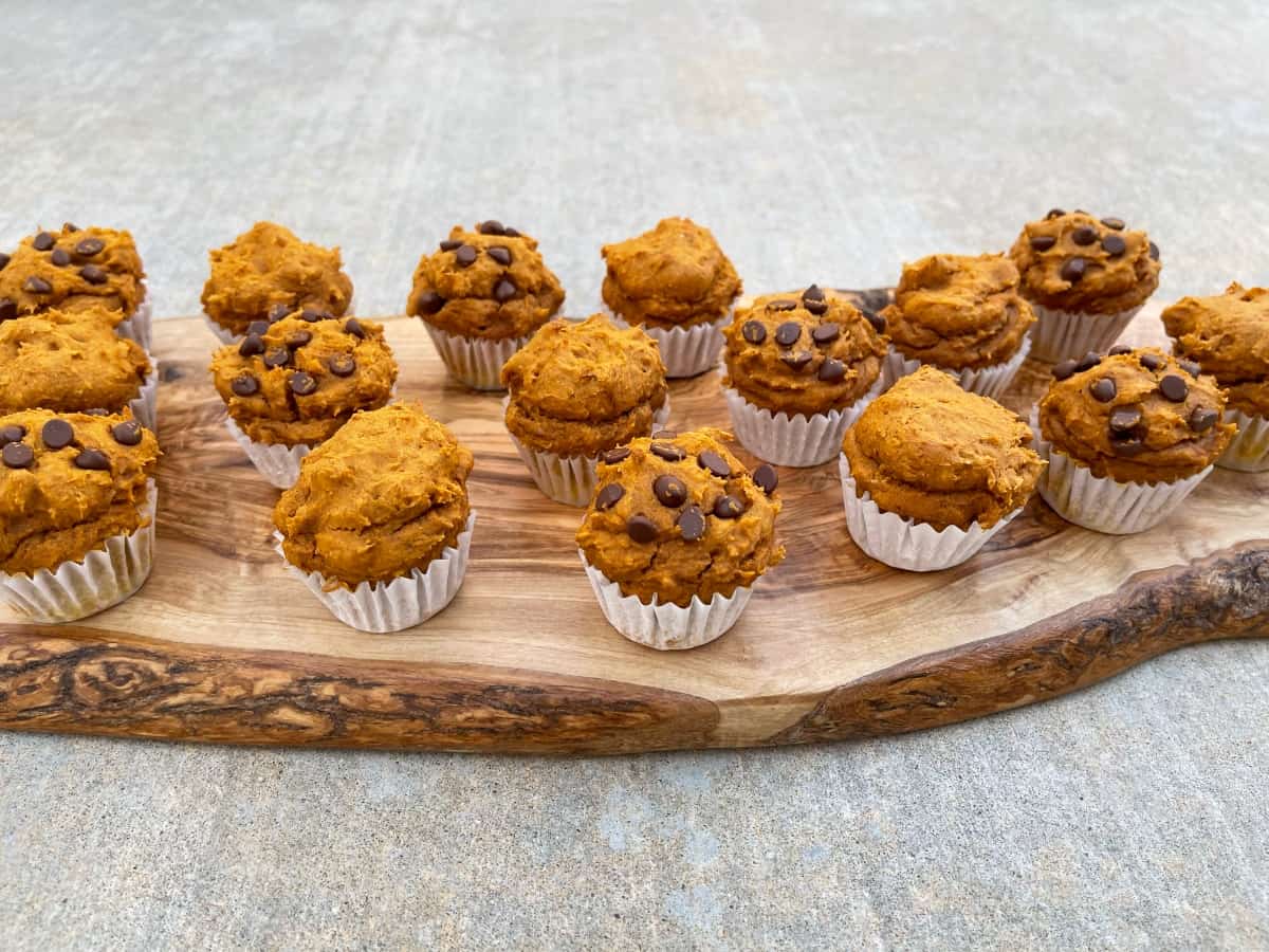 Assortment of plain and mini chocolate chip pumpkin spice cake mix muffins on wood serving platter.