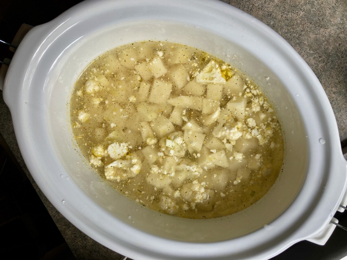 cauliflower, potatoes, garlic, broth in crock pot ready to cook for soup