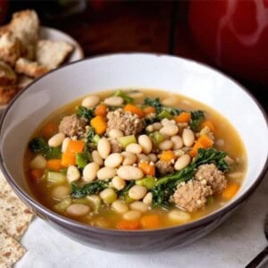 bowl of italian sausage and white bean soup with escarole in a large bowl