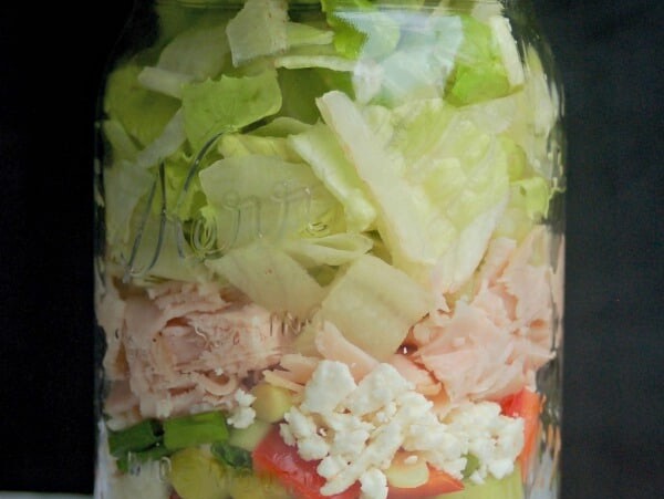 Greek Turkey Feta Salad in a Jar from side black background