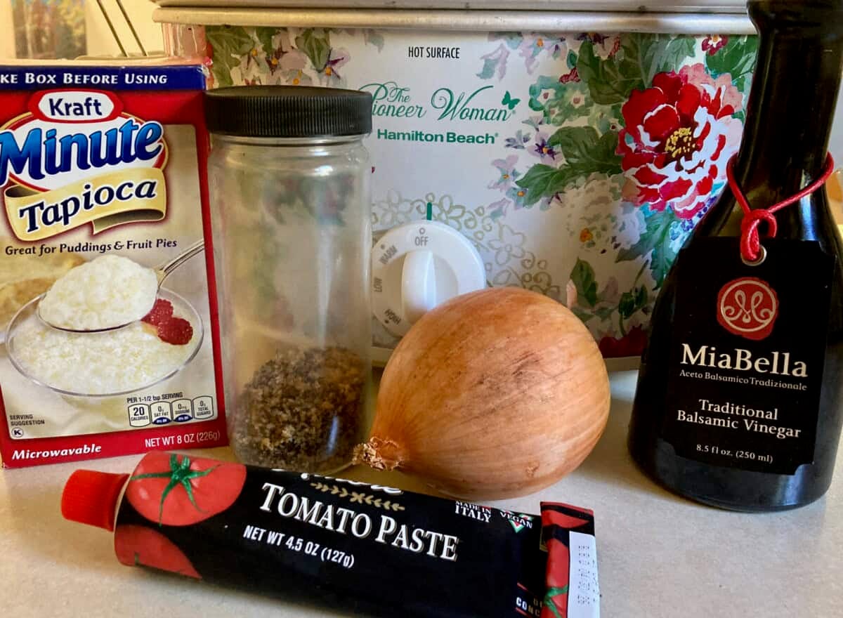 slow cooker behind an onion, bottle of balsamic vinegar, bottle of Montreal steak seasoning, box of Instant Tapioca