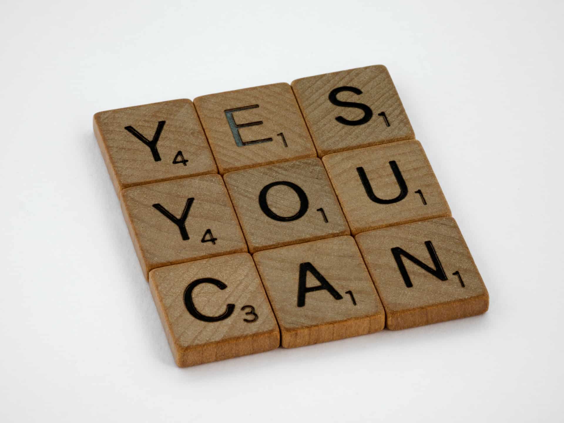 scrabble puzzle pieces spelling "yes you can"