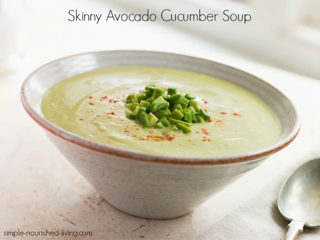 Avocado cucumber soup garnished with chopped avocado and cumin in ceramic bowl with spoon.