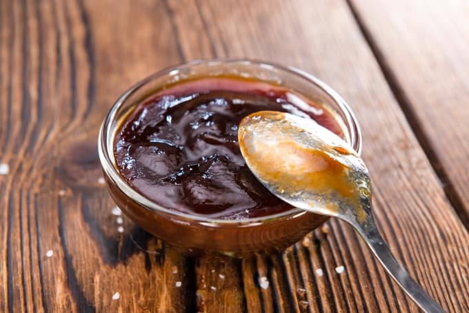 Small glass bowl of barbecue sauce with spoon
