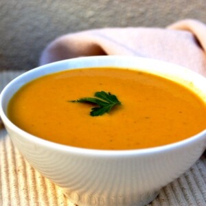pumpkin soup in white bowl on beige mat