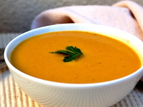 pumpkin soup in white bowl on beige mat