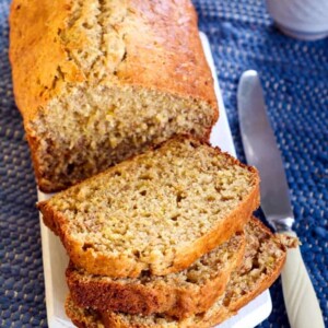 loaf of banana bread on cutting board partially sliced wiih knife alongside