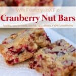 Low-fat cranberry nut bars on white napkin with plate of cranberry bars in background.