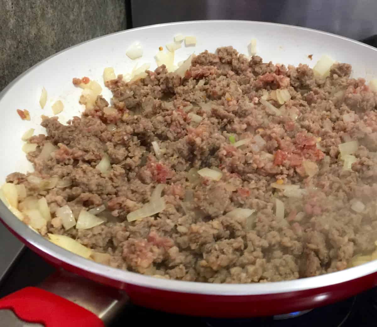 Cooking ground meat and onion in a skillet.
