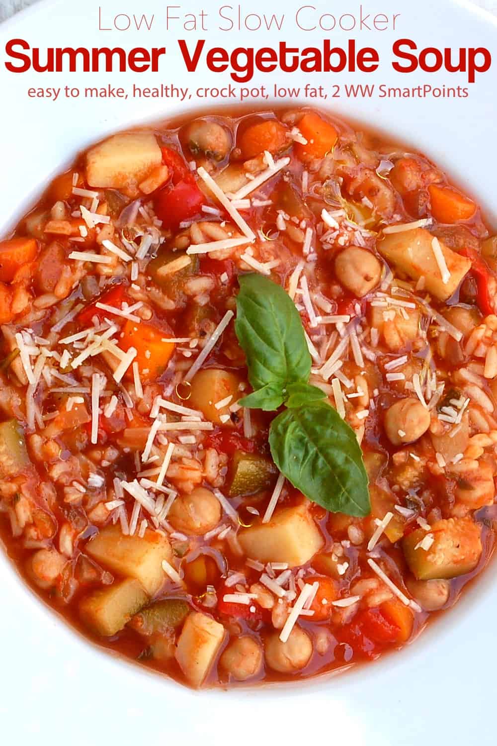 Summer vegetable minestrone soup topped with fresh basil and grated parmesan cheese in a white bowl.