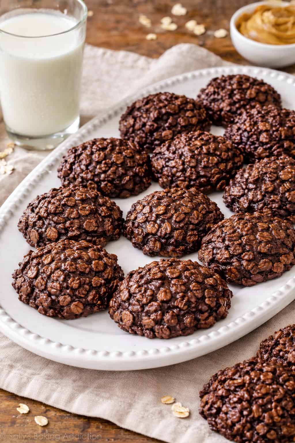 No-Bake Chocolate Peanut Butter Oatmeal Cookies on white serving platter alongside a glass of cold milk.
