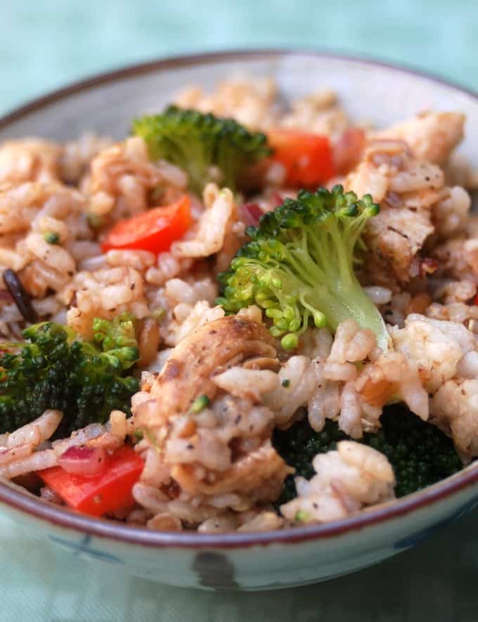 Chicken and brown rice with bell peppers and broccoli in ceramic bowl.